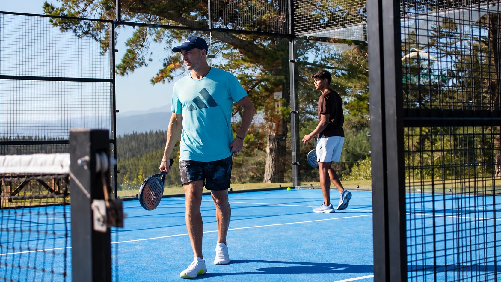 Dos jugadores en una pista exterior rodeada de árboles